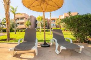 dwa krzesła i parasol na patio w obiekcie Cosy Apartment 2 Bedrooms Golf City w Marakeszu