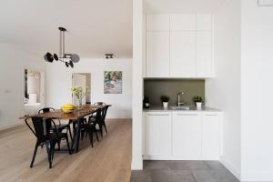 a kitchen and dining room with white cabinets and a table at Luxury Apart - Młyn Maria in Wrocław