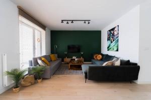 a living room with a blue couch and a green wall at Luxury Apart - Młyn Maria in Wrocław