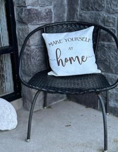 una sedia nera con un cuscino che dica di fare come se fossi a casa tua di Oceanview House a Ballycastle
