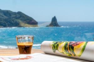 un vaso de cerveza sentado en una mesa junto al océano en Lido Sofia Apartments en Agios Gordios