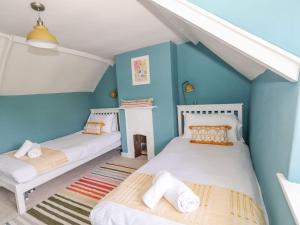 two beds in a room with blue walls at Alice's Cottage in Bridport