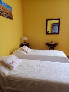2 camas blancas en una habitación amarilla con espejo en LILY - STORIE DEL BOSCO -, en San Felice sul Panaro