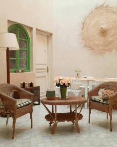 een woonkamer met 2 stoelen en een tafel met bloemen bij Riad Nour, Maison de charme. in Marrakesh