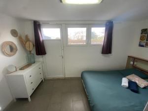 a small bedroom with a bed and two windows at Le Jardin de Sasha in Équemauville +5 photos