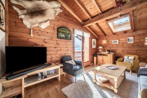 a living room with a large flat screen tv in a log cabin at Chalet Sun River - 8 pers in Morzine
