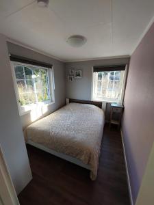 a small bedroom with a bed and two windows at "Huset Alcamaro" 