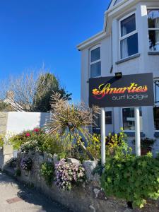 a sign for an entrance to a building with flowers at Smarties Surf Lodge in Newquay