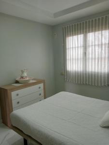 ein Schlafzimmer mit einem Bett, einer Kommode und einem Fenster in der Unterkunft LA RAZÓN DE MI SER in Chiclana de la Frontera
