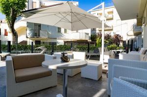 un tavolo con sedie e un ombrellone su un patio di Hotel Bellevue a Cattolica