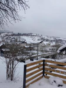 un banc recouvert de neige avec des maisons en arrière-plan dans l'établissement Alissa House, à Borsa