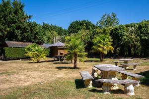 una mesa de picnic y bancos en un parque en Gites - Domaine de Geffosse en Pont-lʼÉvêque