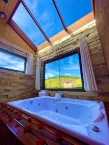 a large tub in a room with a large window at Pousada Verdes Alpes in Santo Antônio do Pinhal +39 photos