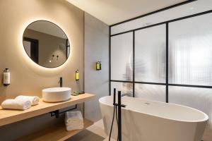 een badkamer met een bad, een wastafel en een spiegel bij Sercotel EsteOeste in Lugo