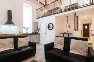 a living room with two leather chairs and a kitchen at The Coach House - Central Hexham in Hexham