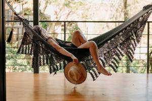 uma mulher sentada numa rede com um chapéu em TreeCasa Hotel & Resort Nicaragua em San Juan del Sur