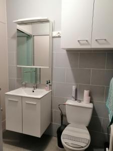 a white bathroom with a toilet and a sink at Les orchidées in Picauville