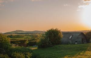 une ancienne grange sur une colline avec le coucher du soleil en arrière-plan dans l'établissement Eco Pod 1 At Tapnell Farm, à Yarmouth