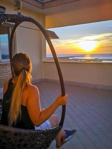 a woman sitting in a hammock watching the sunset at VUEL SEA VIEW HOUSE -10 Minutes from the Airport Fiumicino in Fiumicino