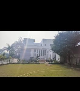 a large white building with a grass field in front of it at M.D. Grand Hotel N Resort in Agra