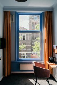 a room with a blue window and a chair at Hotel Omega in Amsterdam