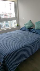 a bed with a blue striped comforter and a window at departamento concon in Concón