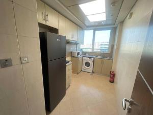 een keuken met een koelkast en een wasmachine bij Nearest to the Airport l Beautiful 1 BR Apt in Abu Dhabi