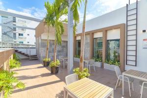 a patio with tables and chairs and palm trees at Modern and cozy 1 bedroom apartment in Santo Domingo