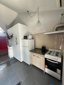 a kitchen with a stove and a white refrigerator at Dpto Santa Rosa in Santa Rosa de Calamuchita