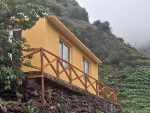 a yellow house on the side of a mountain at Levadinha - Nature guest house in Madalena do Mar