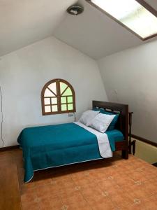 1 dormitorio con 1 cama con manta azul y ventana en Cabañas Lunas del Poás, 