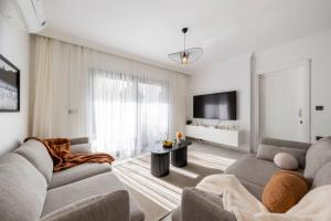 a living room with a couch and a tv at Bodrum Center 2 Bedroom Calm Modern Garden Floor Flat - Yeni Dünya Bodrum in Bodrum City