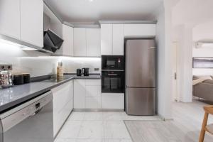 a kitchen with white cabinets and a stainless steel refrigerator at Bodrum Center 2 Bedroom Calm Modern Garden Floor Flat - Yeni Dünya Bodrum in Bodrum City