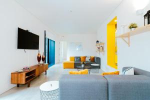 a living room with a couch and a tv at Surf & Sea Suites in Parede