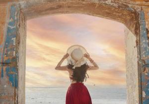 une femme en robe rouge et chapeau à la porte dans l'établissement The Song VT Beach Apartment, à Vung Tau