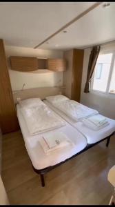 een kleine slaapkamer met 2 bedden met witte lakens bij Mipro mobilhome 6 in Lido di Spina