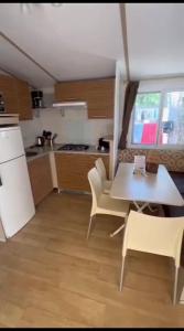 een keuken met een tafel, stoelen en een koelkast bij Mipro mobilhome 6 in Lido di Spina