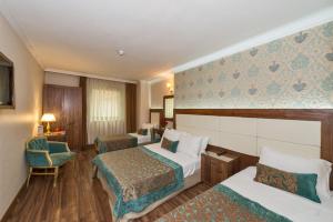 um quarto de hotel com duas camas e uma cadeira em Green Anka Hotel em Istambul