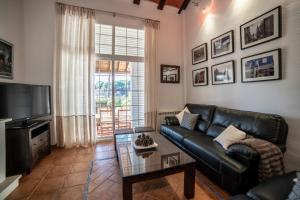 sala de estar con sofá de cuero negro y TV en Casa el Refugio del Lago alojamiento rural, en Córdoba