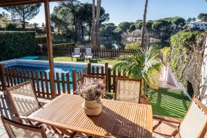 a wooden table and chairs on a patio with a pool at Casa el Refugio del Lago alojamiento rural in Córdoba