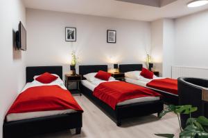 two beds with red pillows in a room at Hotel im Hegen in Oststeinbek