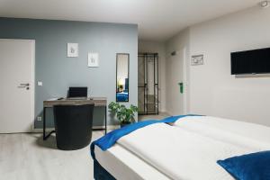 a bedroom with a bed and a desk with a computer at Hotel im Hegen in Oststeinbek