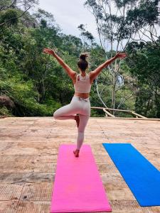 Una donna che fa una posa yoga su un tappetino da yoga di Ella Retreat Glamping Tent on Hill for Nature Lovers a Ella