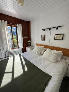 a bedroom with a large white bed with a window at Hotel Au Bon Accueil in Les Deux Alpes