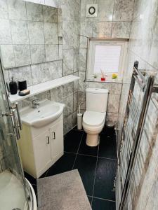 La salle de bains est pourvue de toilettes, d'un lavabo et d'une fenêtre. dans l'établissement Willesden J Guest Home 4, à Londres
