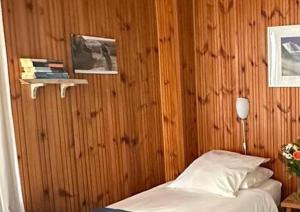 ein Schlafzimmer mit einem Bett und einer Holzwand in der Unterkunft Hotel Au Bon Accueil in Les Deux Alpes