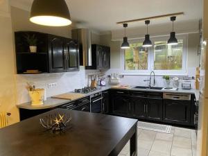 a kitchen with black cabinets and a black table at Joli logement 6 à 8 pers avec terrasse La Cigale in Orbey