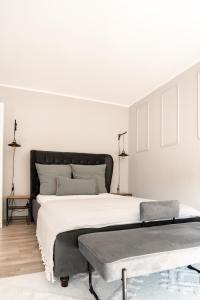 a white bedroom with a large bed and a bench at Buer City Apartment mit Balkon in Gelsenkirchen