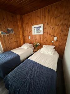 two beds in a room with wood paneling at Hotel Au Bon Accueil in Les Deux Alpes