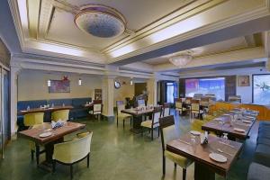 a restaurant with wooden tables and yellow chairs at Hotel Empire Regency in Jaipur